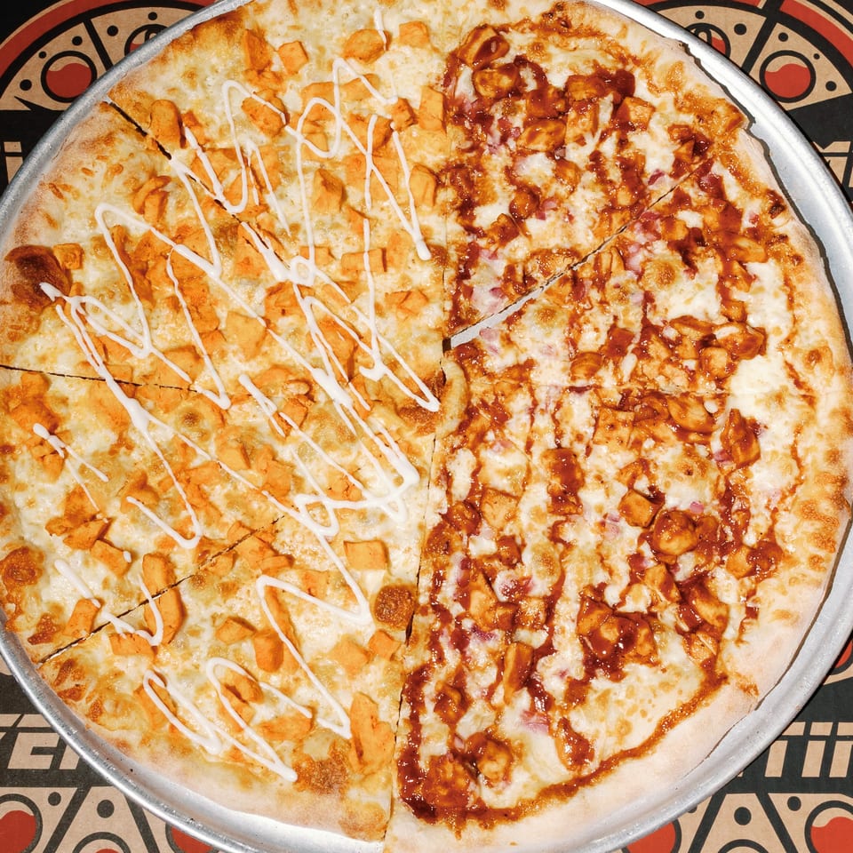 Overtime Pizza's half buffalo chicken, half BBQ chicken pizza on a metal tray.
